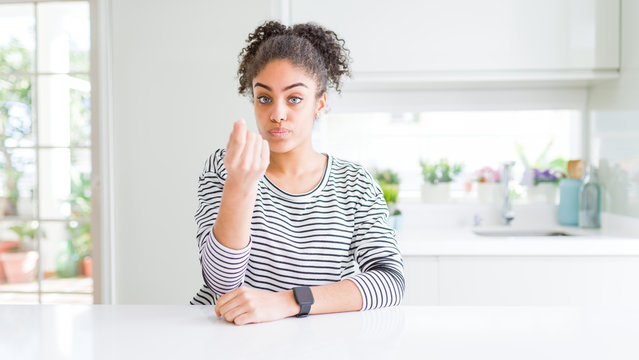 Beautiful african american woman with afro hair wearing casual striped sweater Doing Italian gesture with hand and fingers confident expression