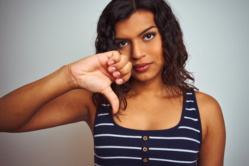 Beautiful transsexual transgender woman wearing striped t-shirt over isolated white background with angry face, negative sign showing dislike with thumbs down, rejection concept