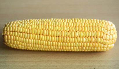 Peeled yellow corn cob on wood background.