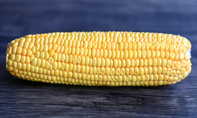 Peeled yellow corn cob on wood background.