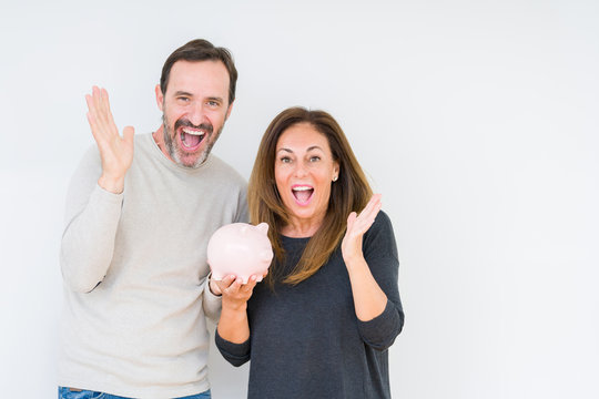 Middle Age Couple Holding Piggy Bank Over Isolated Background Very Happy And Excited, Winner Expression Celebrating Victory Screaming With Big Smile And Raised Hands