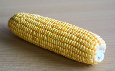 Peeled yellow corn cob on wood background.
