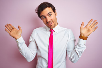 Young handsome businessman wearing shirt and tie standing over isolated pink background clueless...