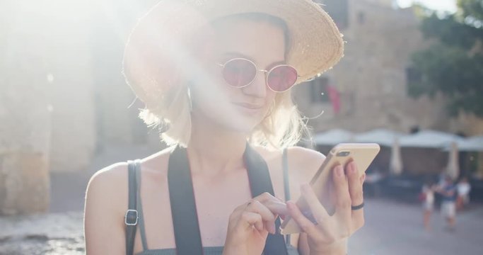 Outdoor portrait of pleasant smiling girl using a smartphone in the street. Close-up nice-looking positive woman with mobile phone in city center. San Gimignano, Italy