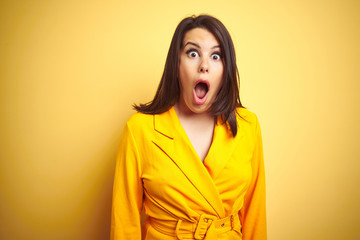 Young beautiful brunette woman wearing elegant dress over yellow isolated background afraid and...