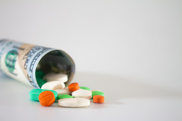 Money from the United States with vibrantly colored medicines on a neutral white background. Concept of health cost. Concept of drug trafficking.