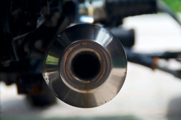 Abstract view of end of round rusted stainless steel motorcycle muffler exhaust pipe.