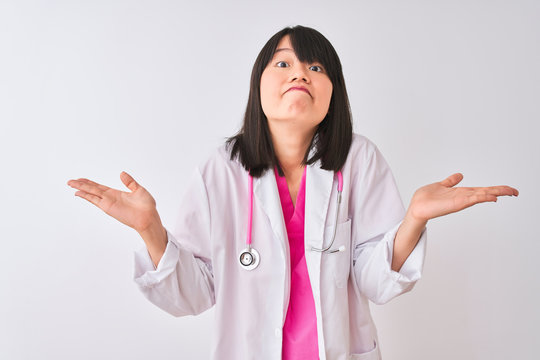 Young beautiful chinese doctor woman wearing stethoscope over isolated white background clueless and confused expression with arms and hands raised. Doubt concept.