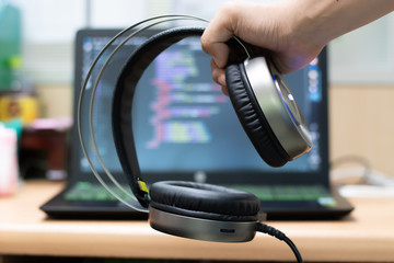 Obraz na płótnie Canvas Hand holding headphone on laptop background.