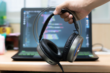 Obraz na płótnie Canvas Hand holding headphone on laptop background.