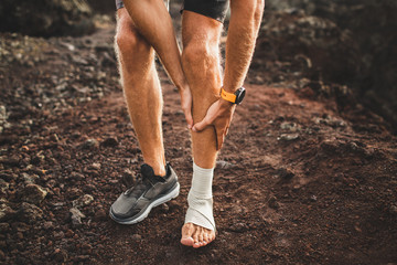 Male runner holding injured leg close-up and suffering with pain. Leg injury. Sprain ligament or...