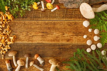 Mushrooms on old wooden background. Card on autumn or summertime. Forest harvest. Boletus, chanterelles, leaves, berries. Flat lay.