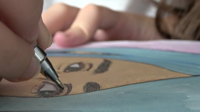 Close up of girl drawing eyelashes on a portrait of a girl with a pen