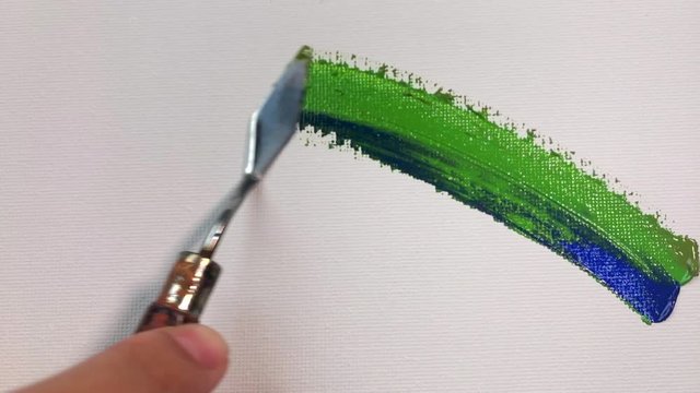 Blue green brush stroke on white canvas close-up