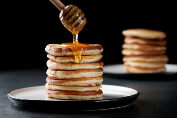 Stack of Pancakes with pouring honey on dark background. decoration concept and breakfast.