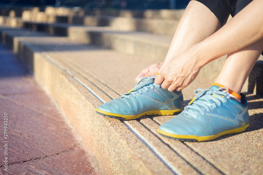 Wall mural running shoes - woman tying shoe laces. closeup of female sport fitness runner getting ready for jog