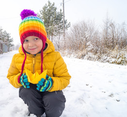 child holds a paper boat in the winter