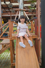 Cute asian little girl having fun to play wooden slide