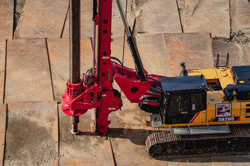 Mobile crane is loading cargo. View on construction site with machinery on construction background.