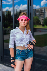 Portrait of an emotional girl in a pink cap visor and protective gloves for rollerblades and...