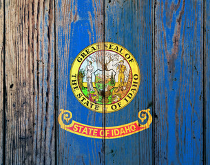 Idaho US state national flag on a gray wooden boards background on the day of independence in different colors of blue red and yellow. Political and religious disputes, customs and delivery.