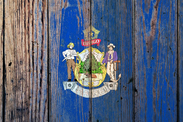 Maine US state national flag on a gray wooden boards background on the day of independence in different colors of blue red and yellow. Political and religious disputes, customs and delivery.