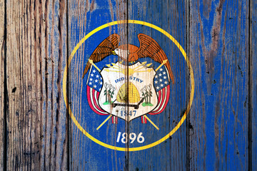 Utah US state national flag on a gray wooden boards background on the day of independence in different colors of blue red and yellow. Political and religious disputes, customs and delivery.