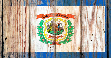 West Virginia US state national flag on a gray wooden boards background on the day of independence in different colors of blue red and yellow. Political and religious disputes, customs and delivery.