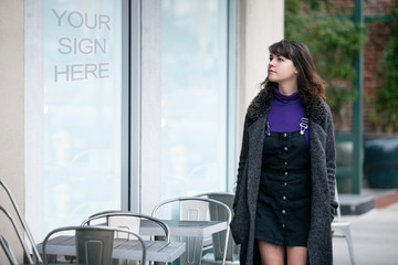 Woman walking outdoors in the city looking at text or logo space on a window display.  Advertising...