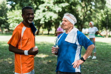 Fototapeta premium selective focus of sportive multicultural senior men holding bottles with water