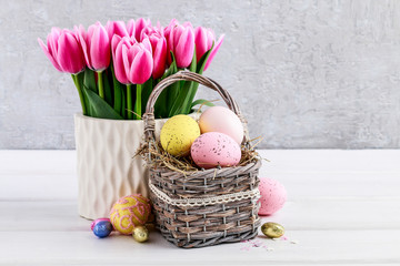 Bouquet of pink tulips and basket of Easter eggs