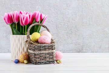 Bouquet of pink tulips and basket of Easter eggs