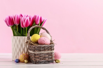Bouquet of pink tulips and basket of Easter eggs