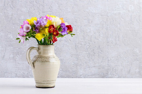 Bouquet of colorful freesia flowers in ceramic vase