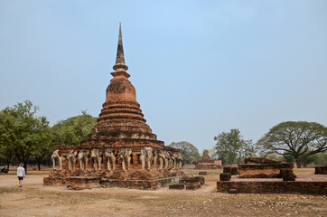 Fototapeta premium Ruins of Temple Wat Chang Lom on the territory of famous Sukhothai Historical Park, a UNESCO World Heritage Site, unique architectural elements in the form of elephants, Thailand