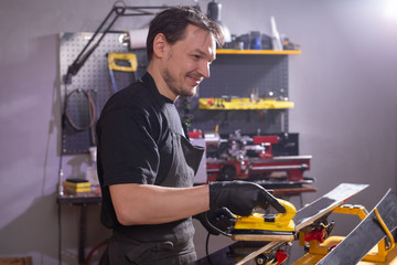 Repair, service and people concept - a man repairing the ski by rubbing a paraffin