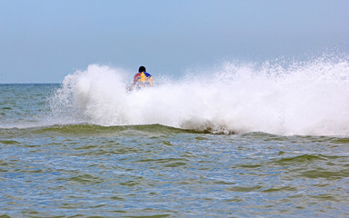 back of the driver on a jet ski rides into the open sea and at high speed creates a lot of spray