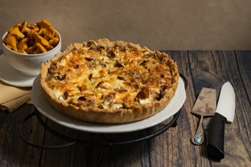 Open pie with chanterelles on shortbread dough. French tart on a wooden background