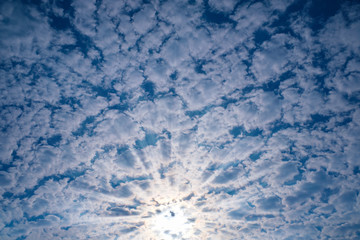 The sun's ray passes through the cirrus clouds in the blue sky.