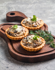 Homemade savory autumn tarts with fresh seasonal mushrooms in a crisp pastry base on gray background