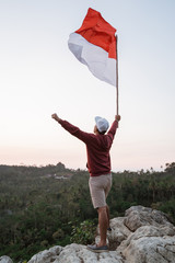 portrait of man on top of the hill in the morning rising indonesian flag celebrating independence day