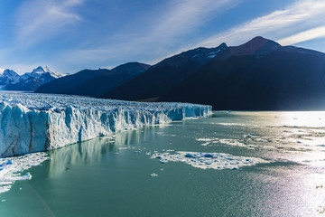 Amazing view of Perito Moreno glacier, blue ice burg glacier with golden sun light shinning through...