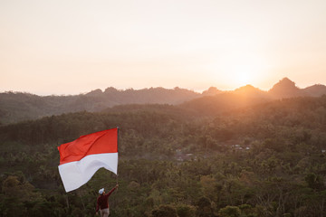 asian man with indonesian flag of indonesia on top of the mountain