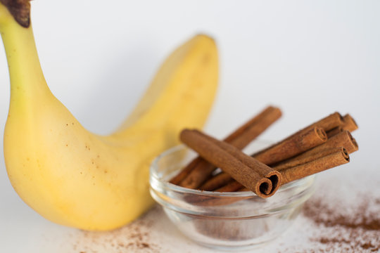 banana and cinnamon sticks in a bow on white background