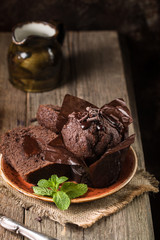 Homemade delicious chocolate muffins with mint and chocolate on wooden background close-up