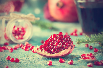 Piece of ripe pomegranate fruit with fir tree branches on blue vintage background