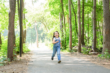 Fototapeta na wymiar Children, childhood and nature concept - Portrait of beautiful small child girl running through the park