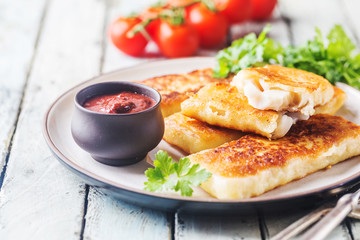Crumbed golden fried fish fingers served with tartar sauce and salad on a white rustic wooden background