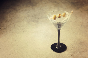 Cocktail martini with olives on stone background, copy space