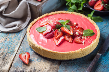 Tart with strawberries and whipped mascarpone cream decorated with fresh strawberry over wooden rustic background